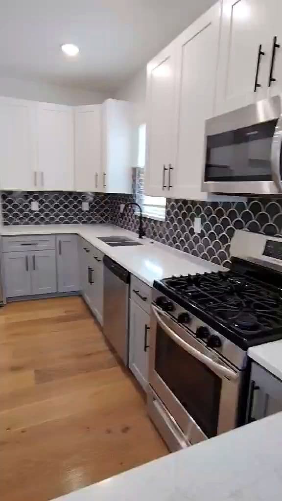 New white kitchen with a scalloped black backsplash and quartz counters