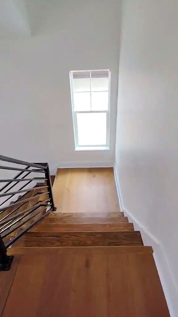 Open oak staircase with a black railing in a newly built home
