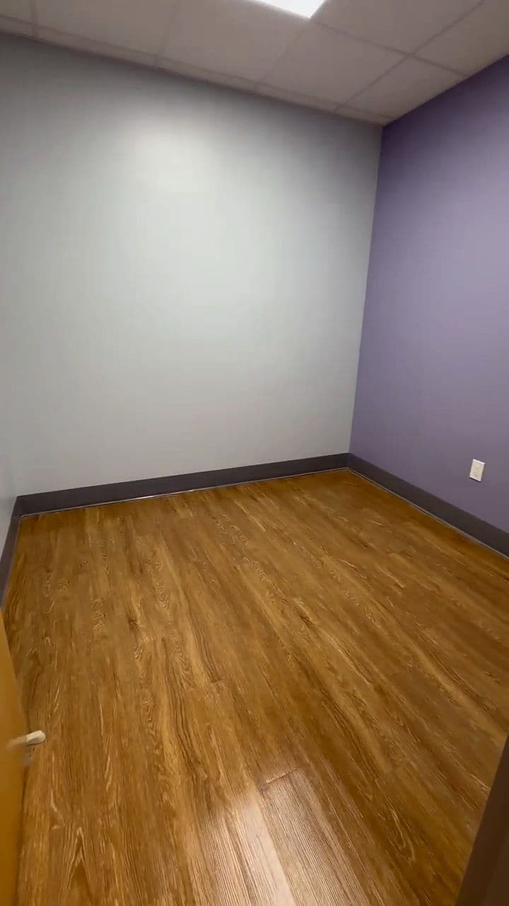 Empty treatment room with lavender walls and a polished floor in afternoon light