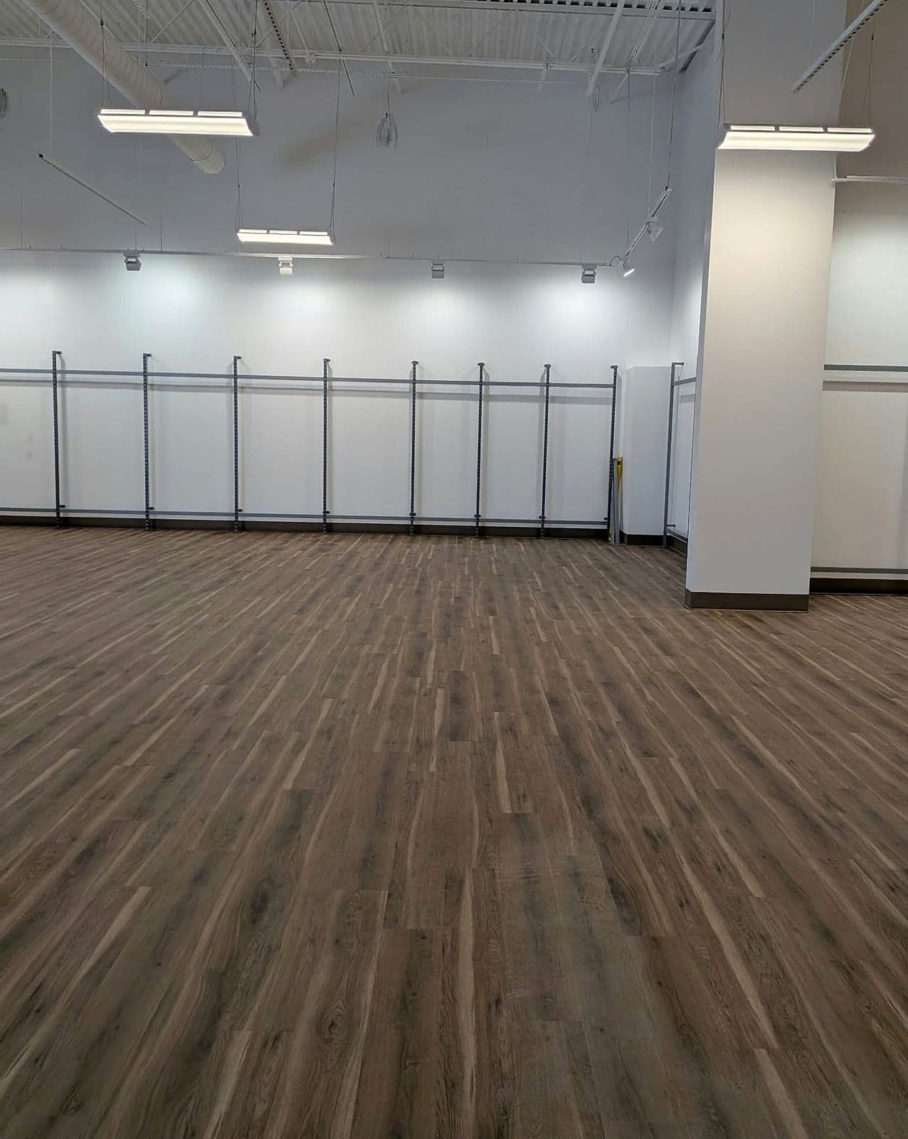 Spotless new plank floor along an empty sales wall in a retail store build-out
