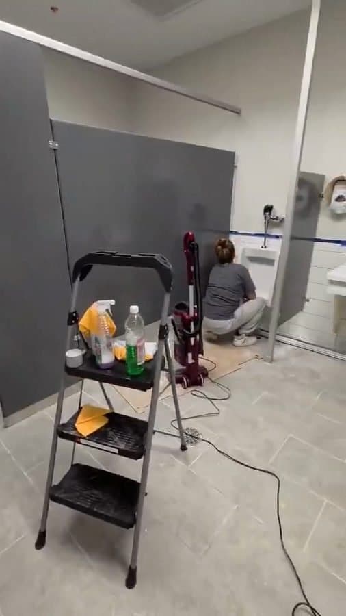 Two crew members detailing a new multi-stall restroom in a retail store build-out