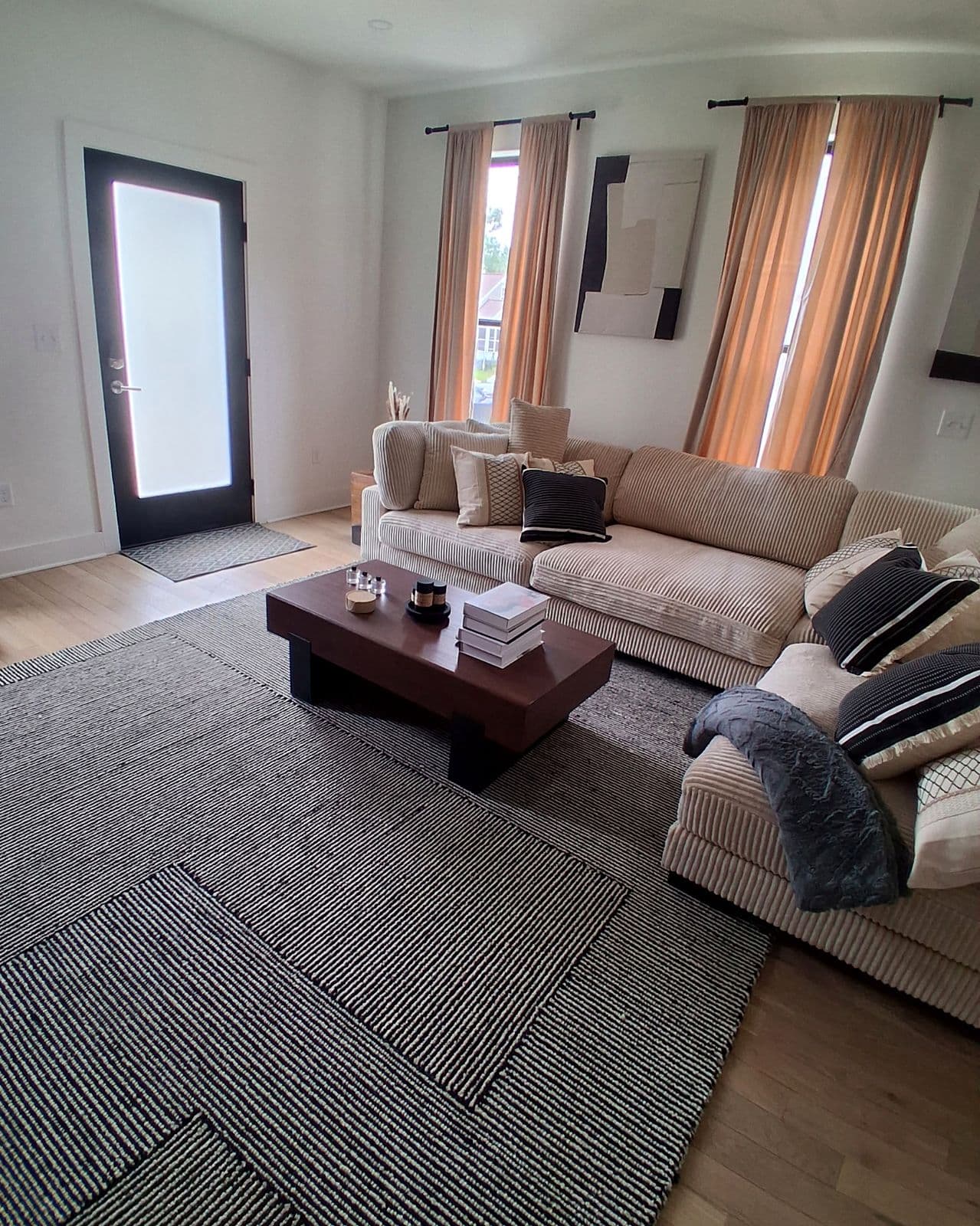 Living room with a cream sectional, striped rug and walnut coffee table, ready for guests